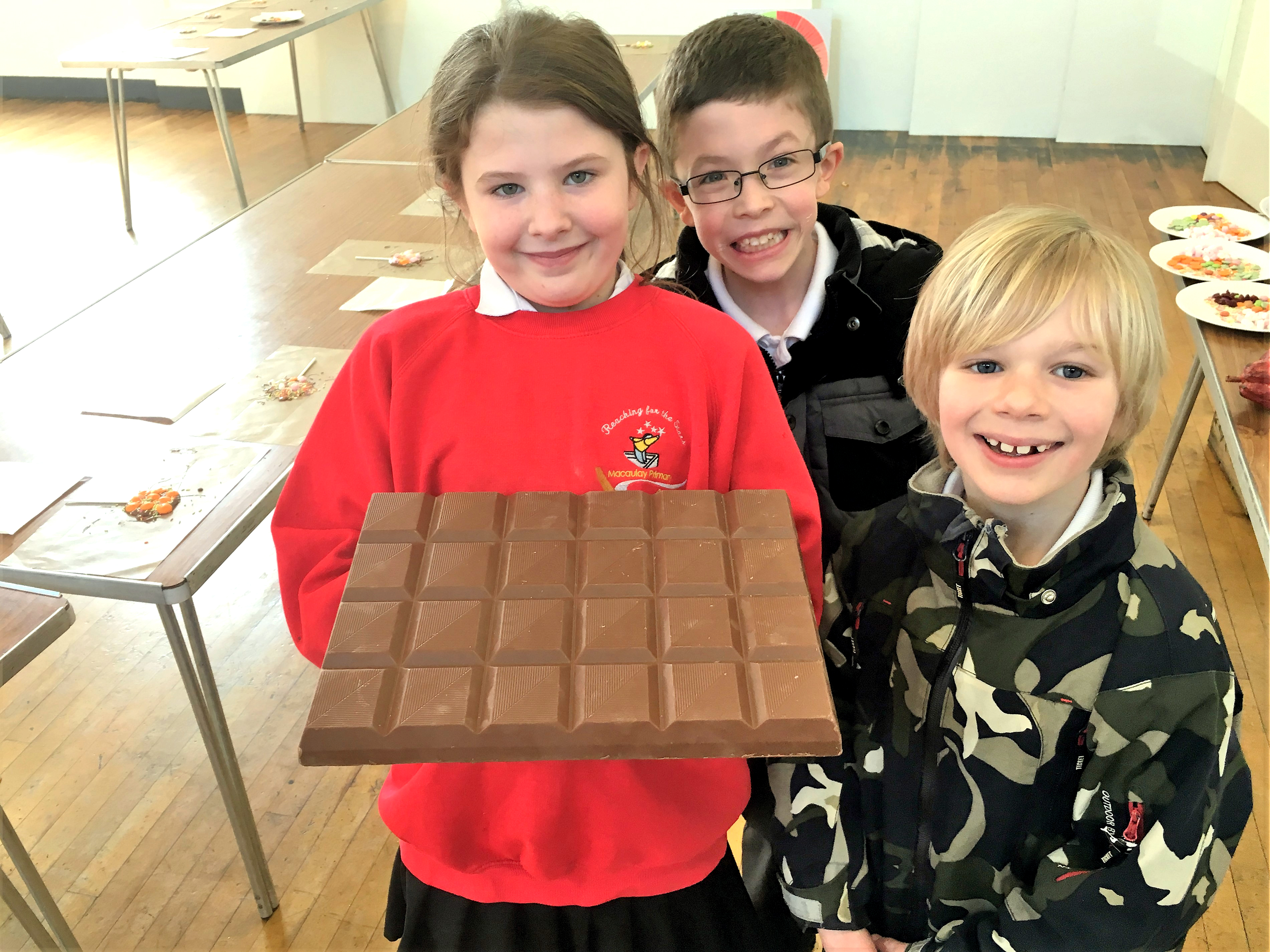 3 kids holding large chocolate bar
